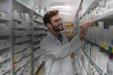 Apotheker im weißen Kittel sortiert Medikamente im Backoffice einer modernen Apotheke