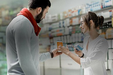 Kunde zeigt Apothekerin eCoupon auf Smartphone