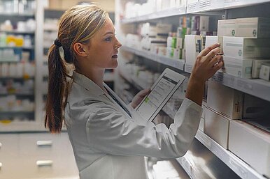 Apothekerin prüft Medikamente im Regal