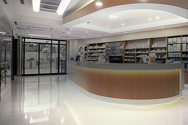 Moderne Apotheke mit beleuchtetem Empfangstresen und gut sortierten Regalen im Hintergrund