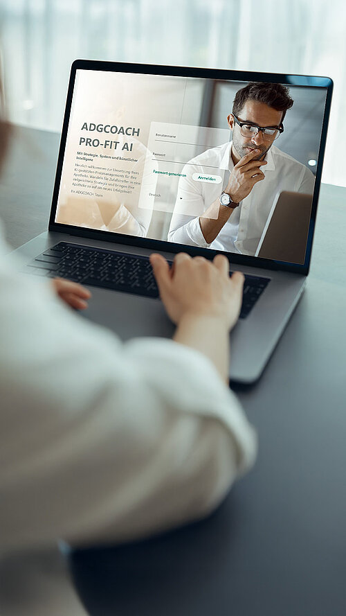 Person arbeitet im modernen Büro an Laptop mit geöffneter ADGCOACH PRO-FIT AI Login-Seite