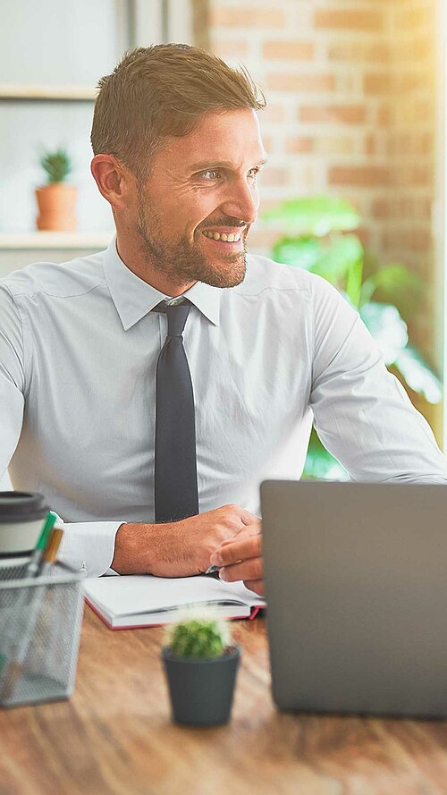 Zwei Geschäftsleute im Gespräch in einem modernen Büro, mit Laptop und Kaffeetassen auf dem Tisch