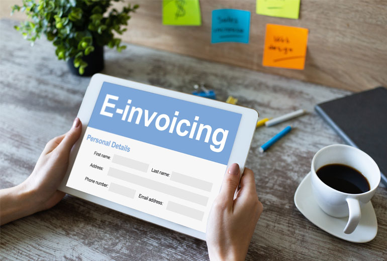 Hände halten Tablet mit Schriftzug E-Invoicing