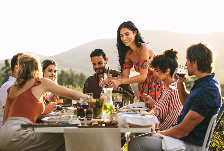 Fröhliche Menschen essen draußen gemeinsam am Tisch