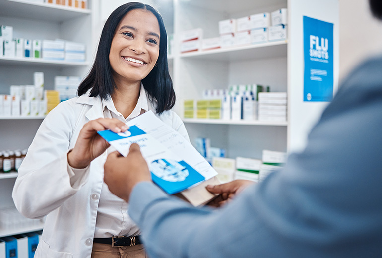 Freundliche Apothekerin überreicht einem Kunden einen Flyer