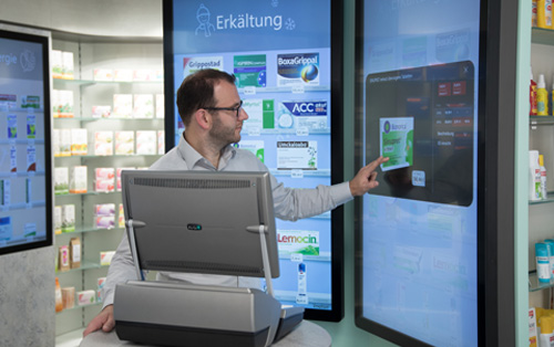 Apotheker Andreas Bühler am HV-Tisch seiner Apotheke mit ADG Kassensystem und Digitaler Sichtwahl