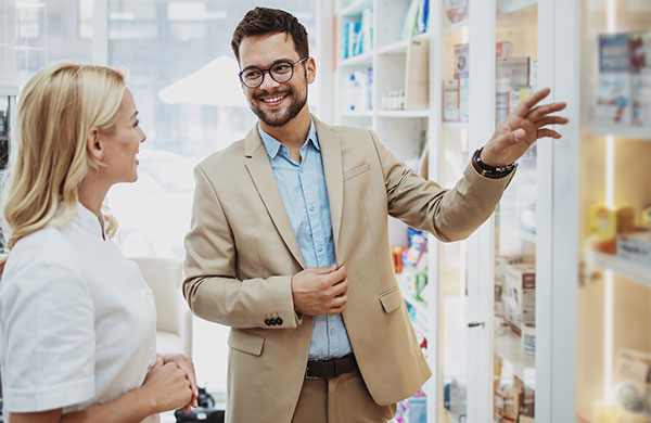 Berater zeigt Apothekerin etwas am Regal