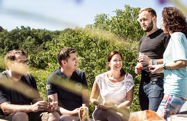 Mitarbeiter sitzen draußen zusammen beim Picknick